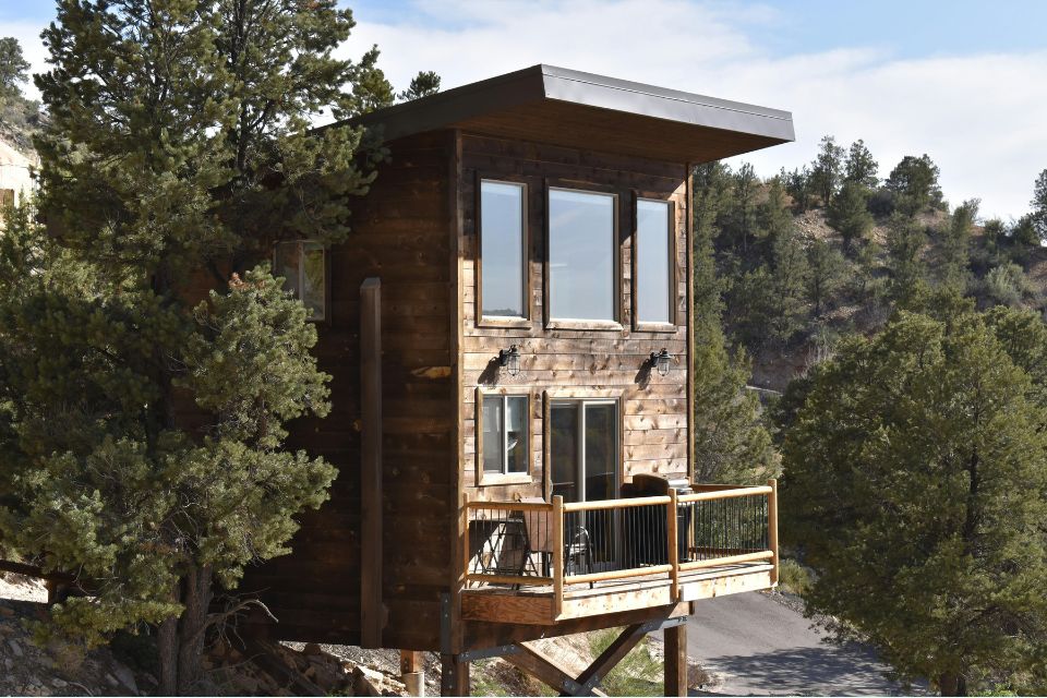Treehouse Cabin Elevated treehouse cabin nestled among tall trees, featuring a wooden deck and large windows overlooking the forest canopy
